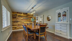 A dining room with a wooden wall, a chandelier, and a cabinet with glass doors. - Entire Spacious, Cozy home with backyard retreat (Norman)