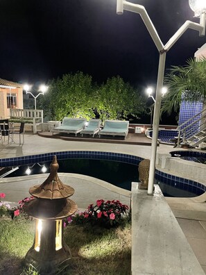 Una piscina al aire libre, sillones reclinables de piscina