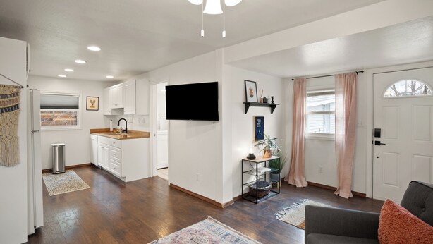 A modern kitchen with white cabinets, a black countertop, and a built-in TV. - Downtown CDA Tiny House-Walk to the Lake (Coeur d'Alene)