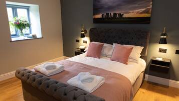 Quarto com cama grande, duas mesinhas de cabeceira, janela com vista e um quadro na parede.