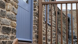 Un bâtiment en pierre avec un escalier en bois menant à une porte ornée d’un panneau bleu.