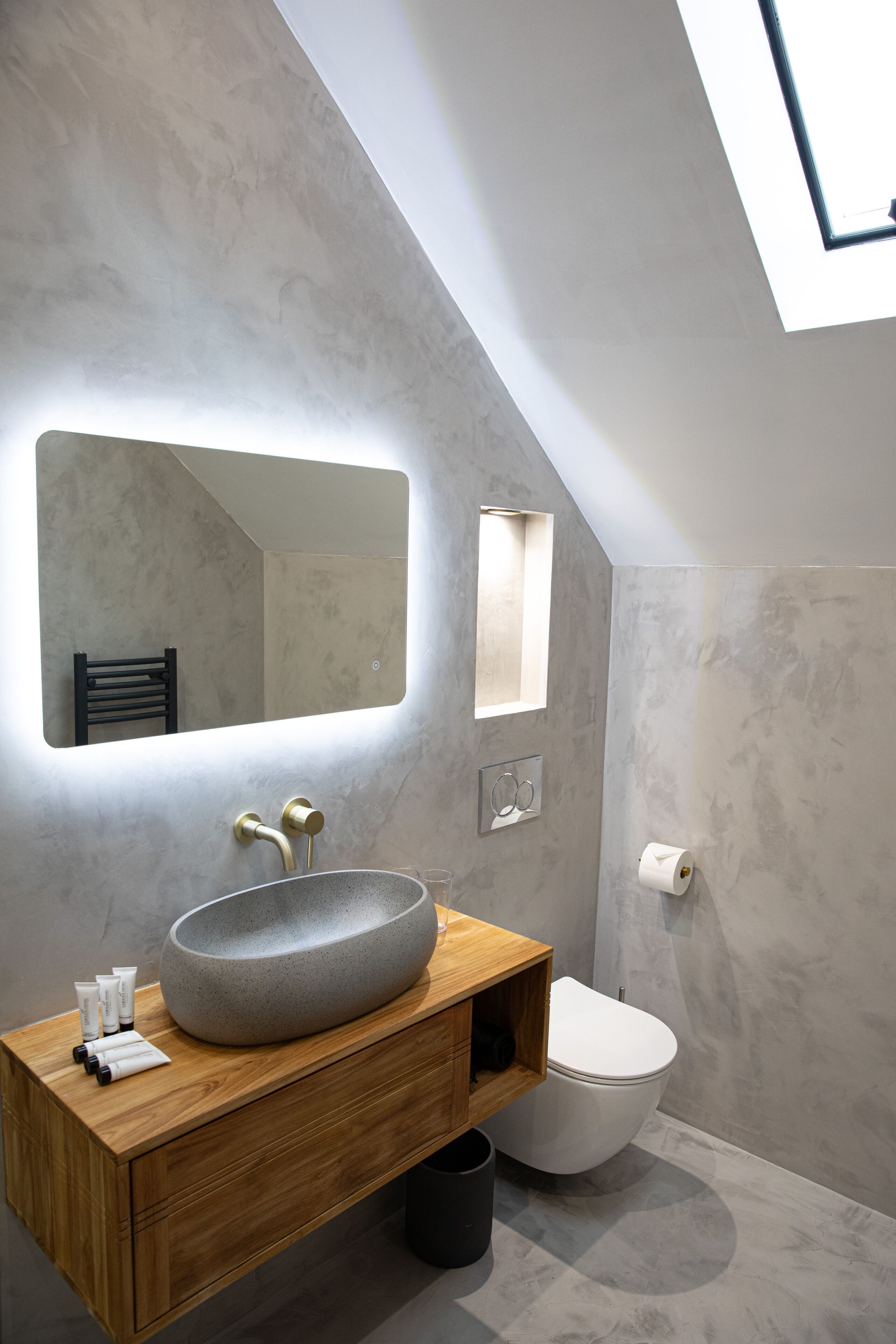 Une salle de bain moderne dotée d’une grande verrière, d’un lavabo sur pied et de toilettes.