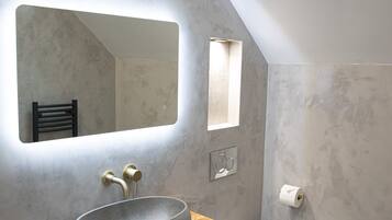 Une salle de bain moderne dotée d’une grande verrière, d’un lavabo sur pied et de toilettes.