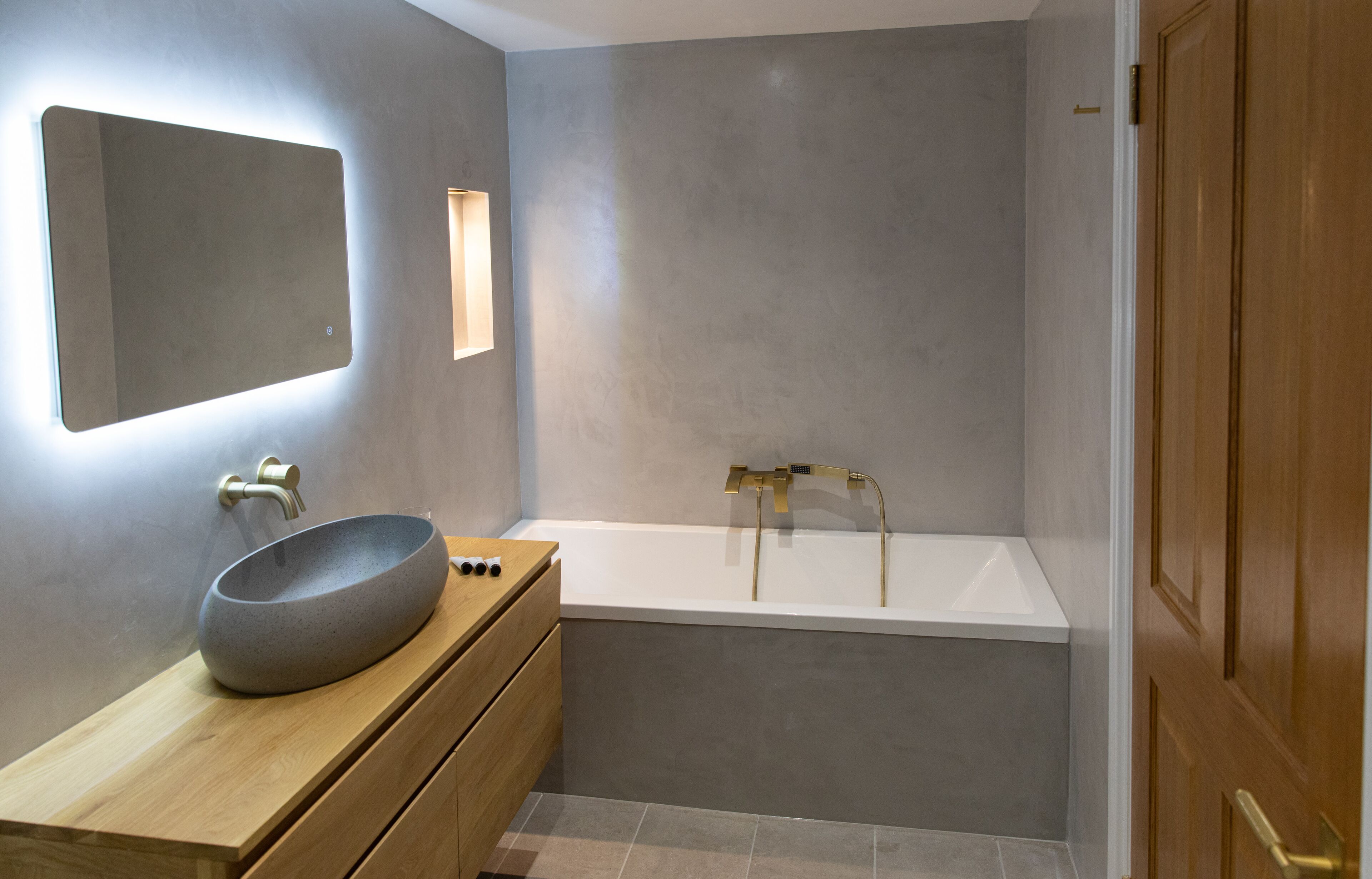 A modern bathroom with a round vessel sink, wooden vanity, and a freestanding bathtub.
