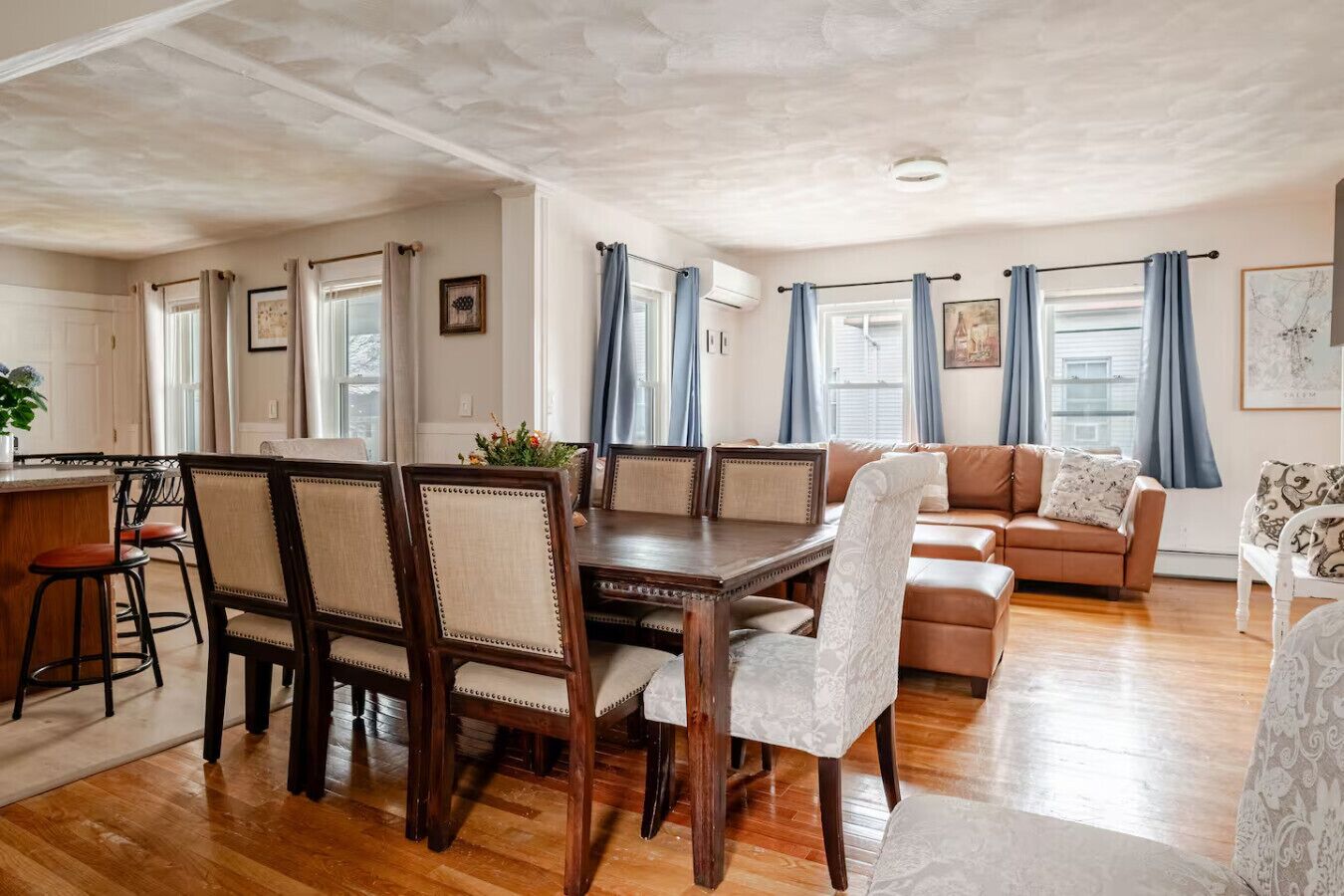 Un vaste espace de vie comprenant une table à manger en bois, un canapé et un coin cuisine avec un bar.