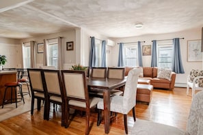 Un amplio salón con una mesa de comedor de madera, un sofá y una zona de cocina con barra.
