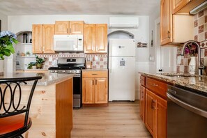 Une cuisine avec des meubles de rangement en bois, un four à micro-ondes, une cuisinière et un réfrigérateur.