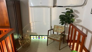 A small room with a wooden chair, a green basket, and a potted plant.