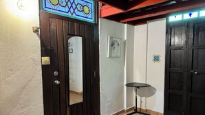 A hallway with a wooden door, a small round table, and a tiled floor.