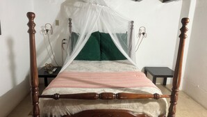 A four-poster bed with a canopy, a bedside table, and a nightstand.