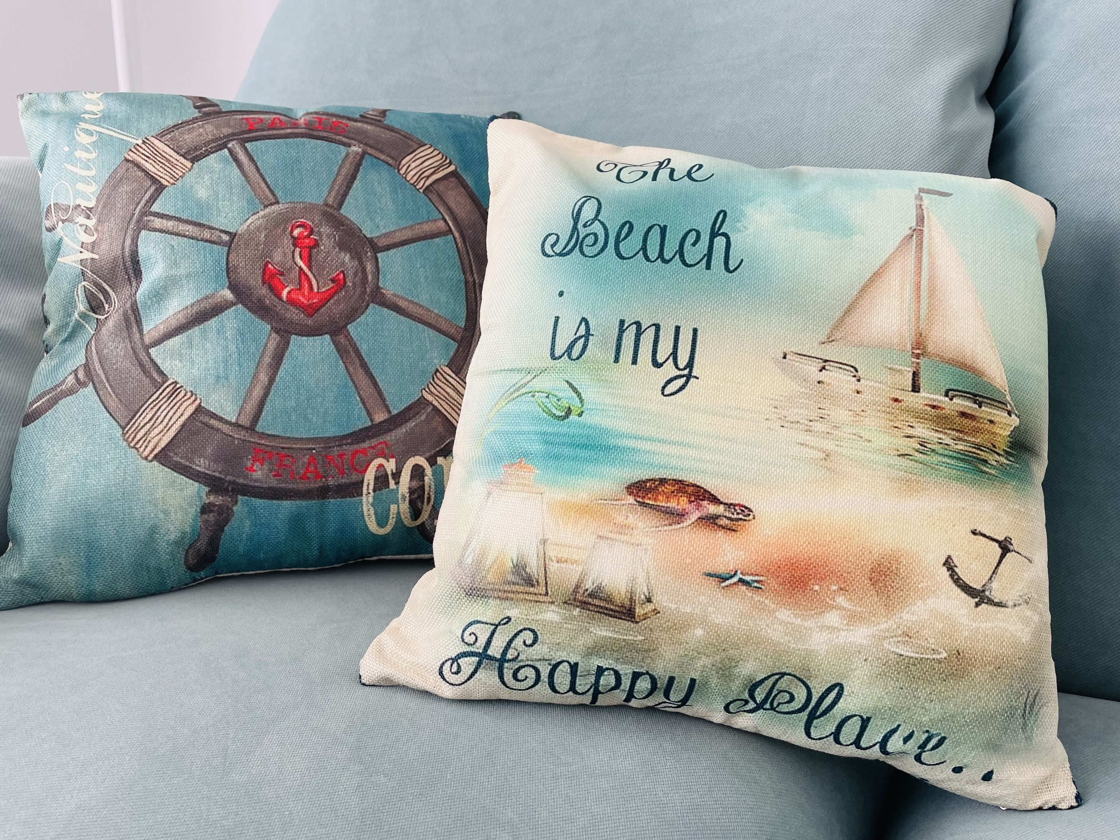 Two decorative pillows with nautical themes, one featuring a ship's wheel and the other with a sailboat and anchor.