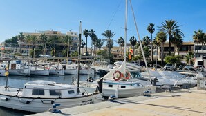 A marina with several boats docked, surrounded by palm trees and buildings. - - BE OUR GUEST! - Sea, pleasure, private roof terrace (Ses Salines)