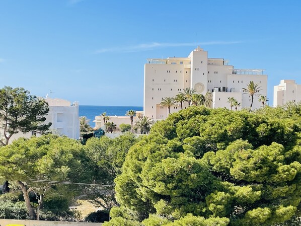 A coastal building with multiple floors, surrounded by lush greenery and palm trees.