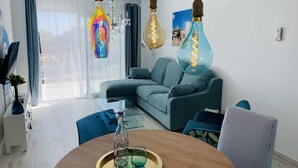 A modern living room with a teal sofa, a glass coffee table, and hanging light fixtures. - - BE OUR GUEST! - Sea, pleasure, private roof terrace (Ses Salines)