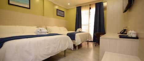 Habitación de hotel con dos camas, un escritorio, una silla, un televisor y una ventana con cortinas.