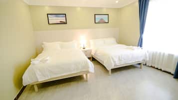 Una habitación de hotel con dos camas, una mesita de noche y un ventanal con cortinas.