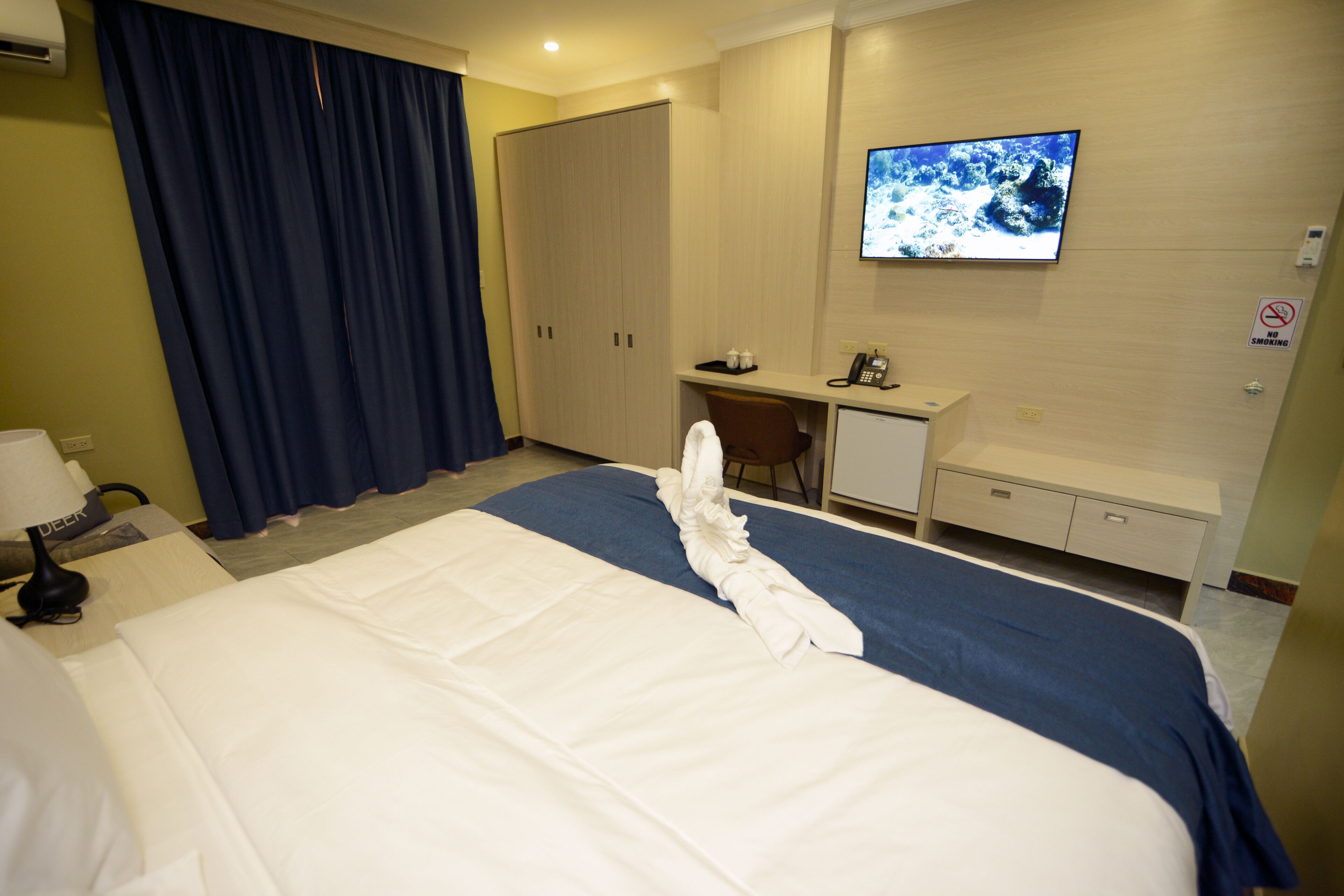 Une chambre d’hôtel équipée d’un lit, d’un bureau, d’une télévision et d’une armoire.