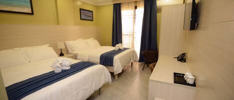 A hotel room with two beds, a desk, a chair, a TV, and a window with curtains.