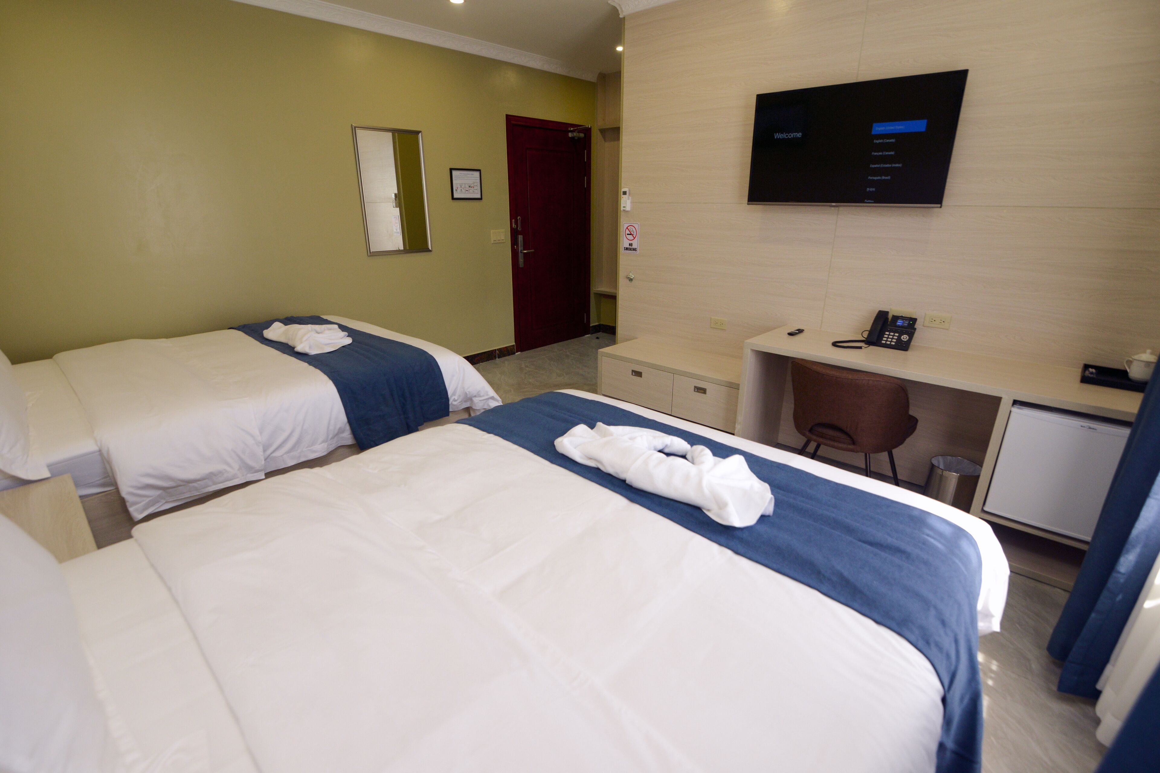 Een hotelkamer met twee bedden, een bureau, een televisie en een telefoon.