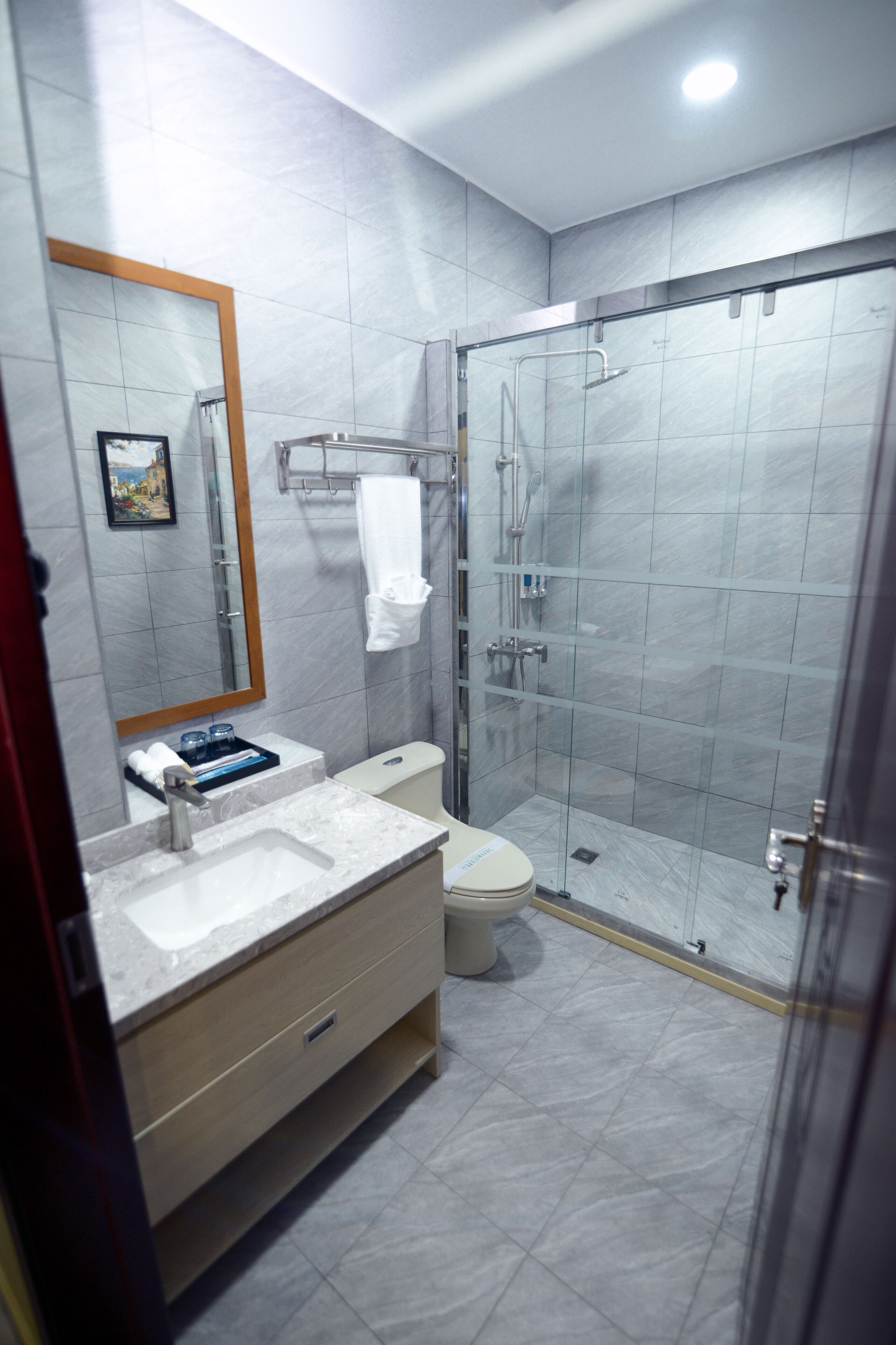 Une salle de bain moderne avec une douche à parois de verre, des toilettes blanches et un lavabo en marbre.