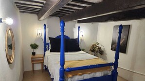 Une chambre à coucher avec un lit à baldaquin, une table de chevet, un miroir et des lampes fixées au mur.