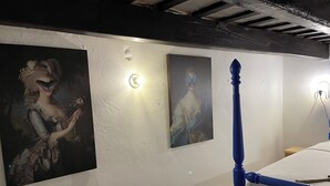 Une pièce comprenant un lit, une lampe fixée au mur et deux tableaux encadrés.