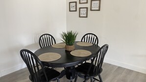 Et spisebord med fire sorte stole, en vævet servietring og en lille potteplante.
