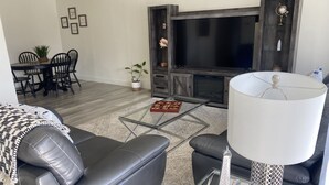 En moderne stue med en lædersofa, et glasbord og en lampe.