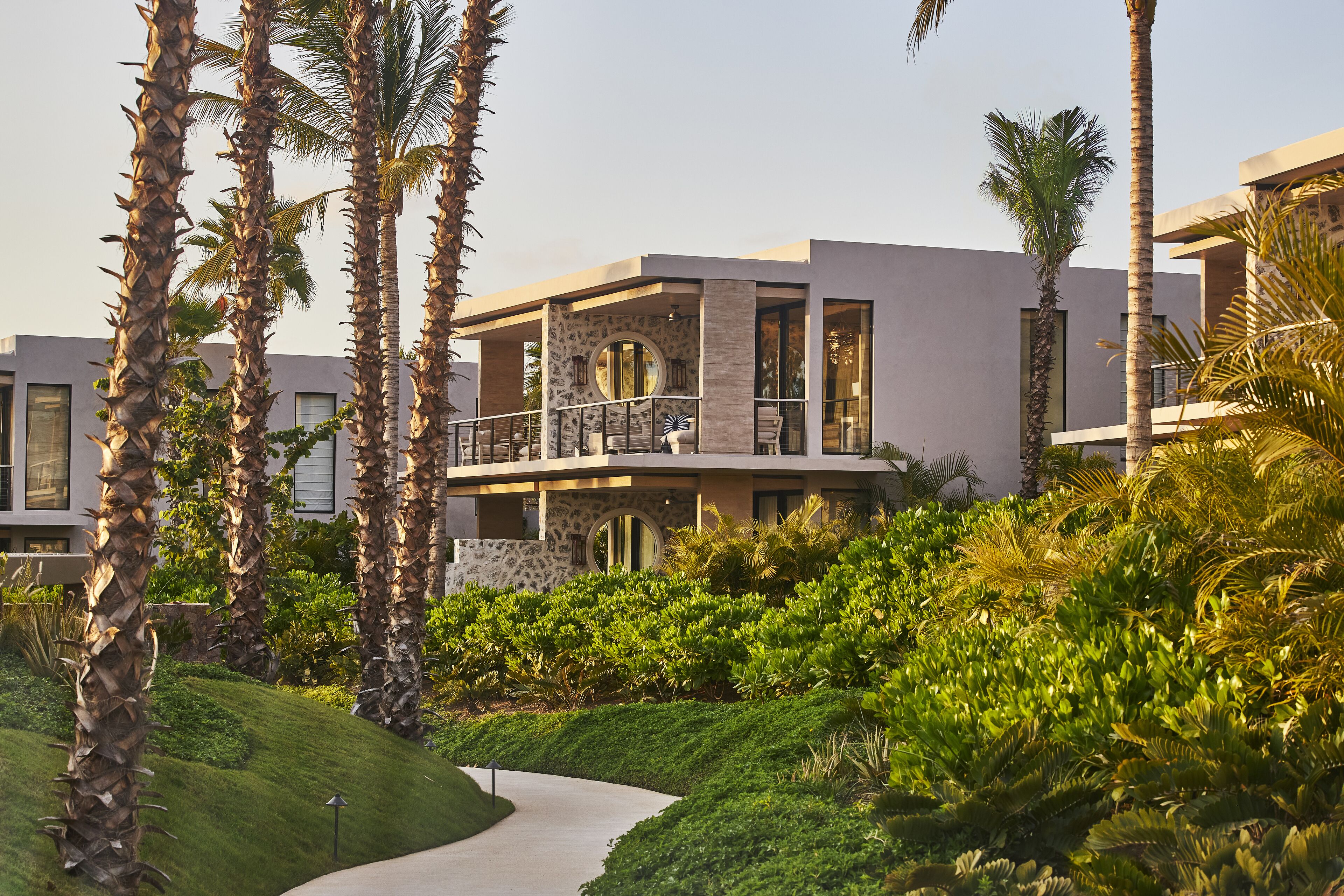 A modern hotel with a stone facade, large windows, and a balcony.