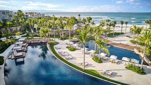Un resort con piscina, palmeras y vista al océano.