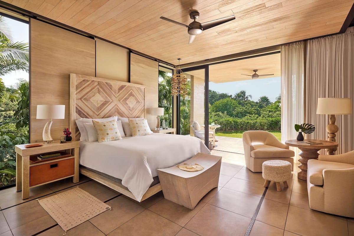 Un dormitorio moderno con una cama grande, un escritorio, una silla y vistas al exterior.