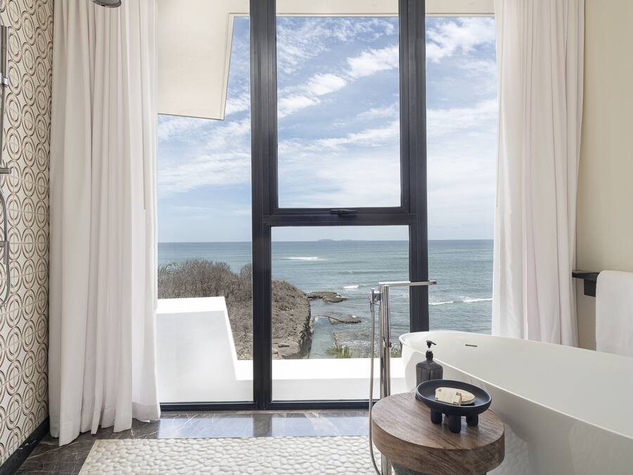 A modern bathroom with a large window, a bathtub, and a shower.