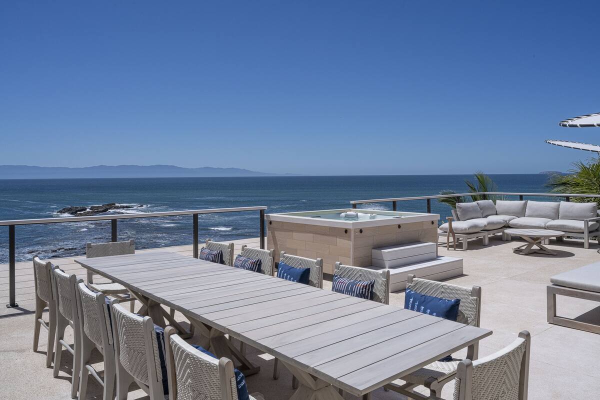 Una terraza con vista al océano, que incluye una mesa y sillas, un sofá y una tumbona.