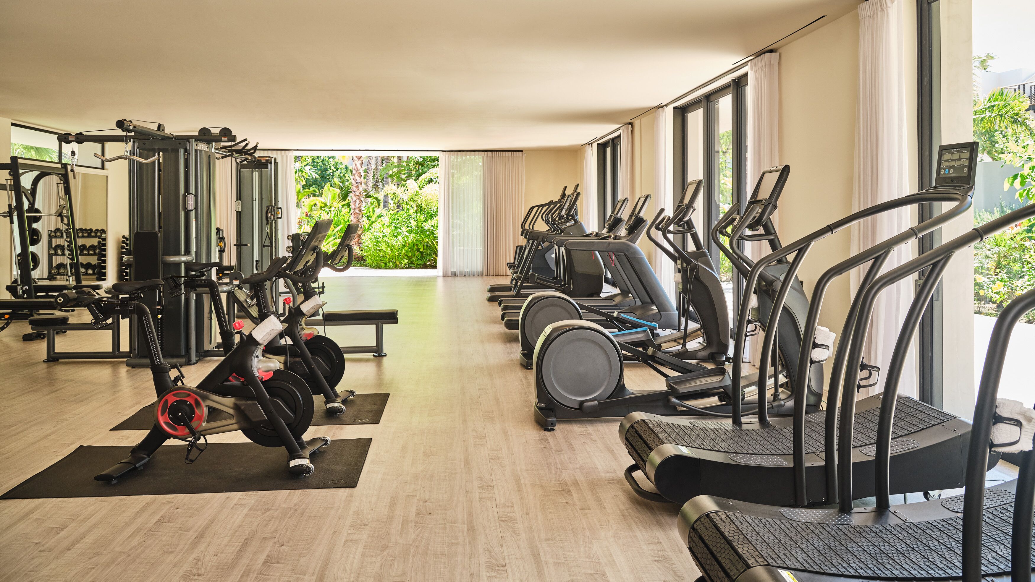 Ein Fitnessraum mit Cardiogeräten, Krafttrainingsgeräten und einem Spiegel.