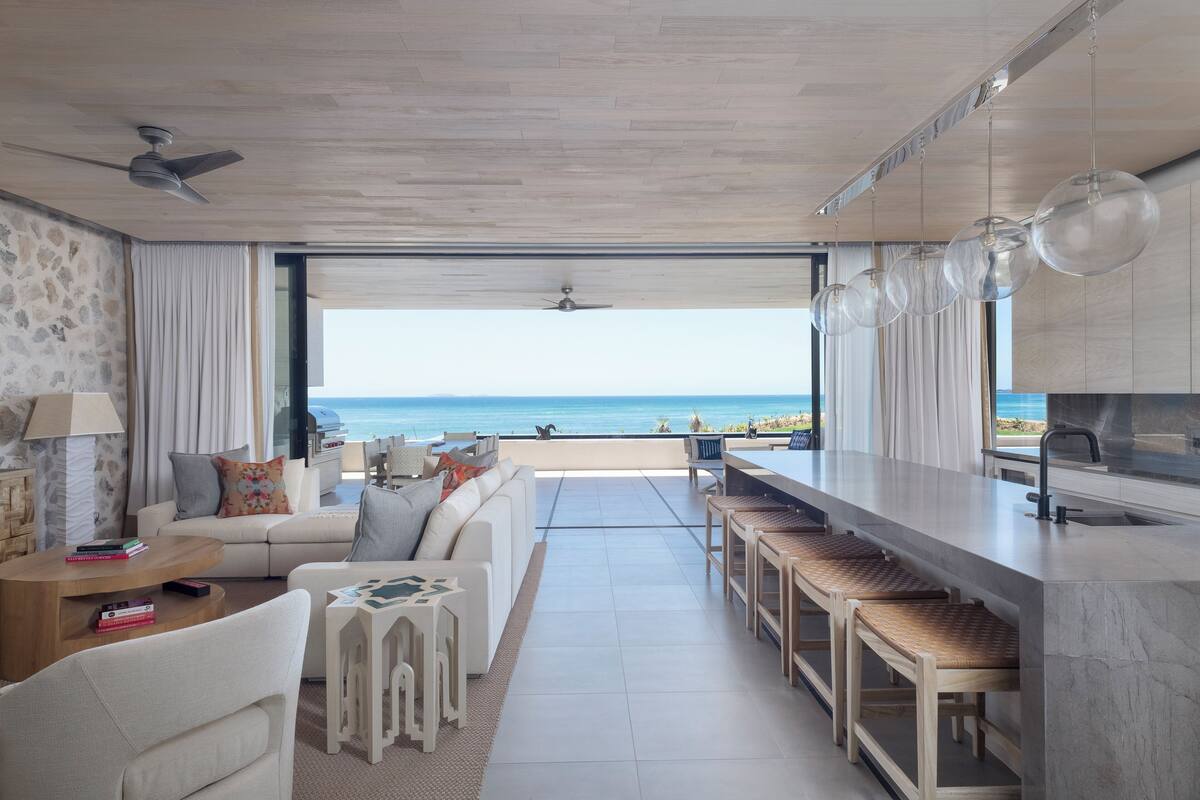 Una sala de estar moderna con un sofá, una mesa de centro y vistas al océano.