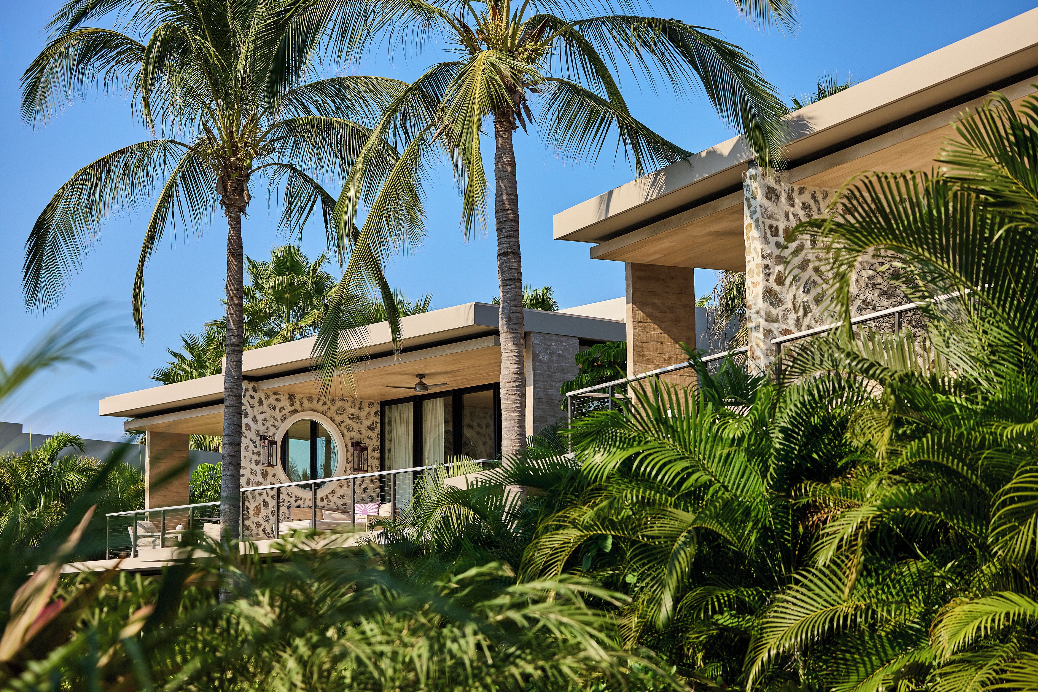 A modern building with a circular window, palm trees, and a balcony.