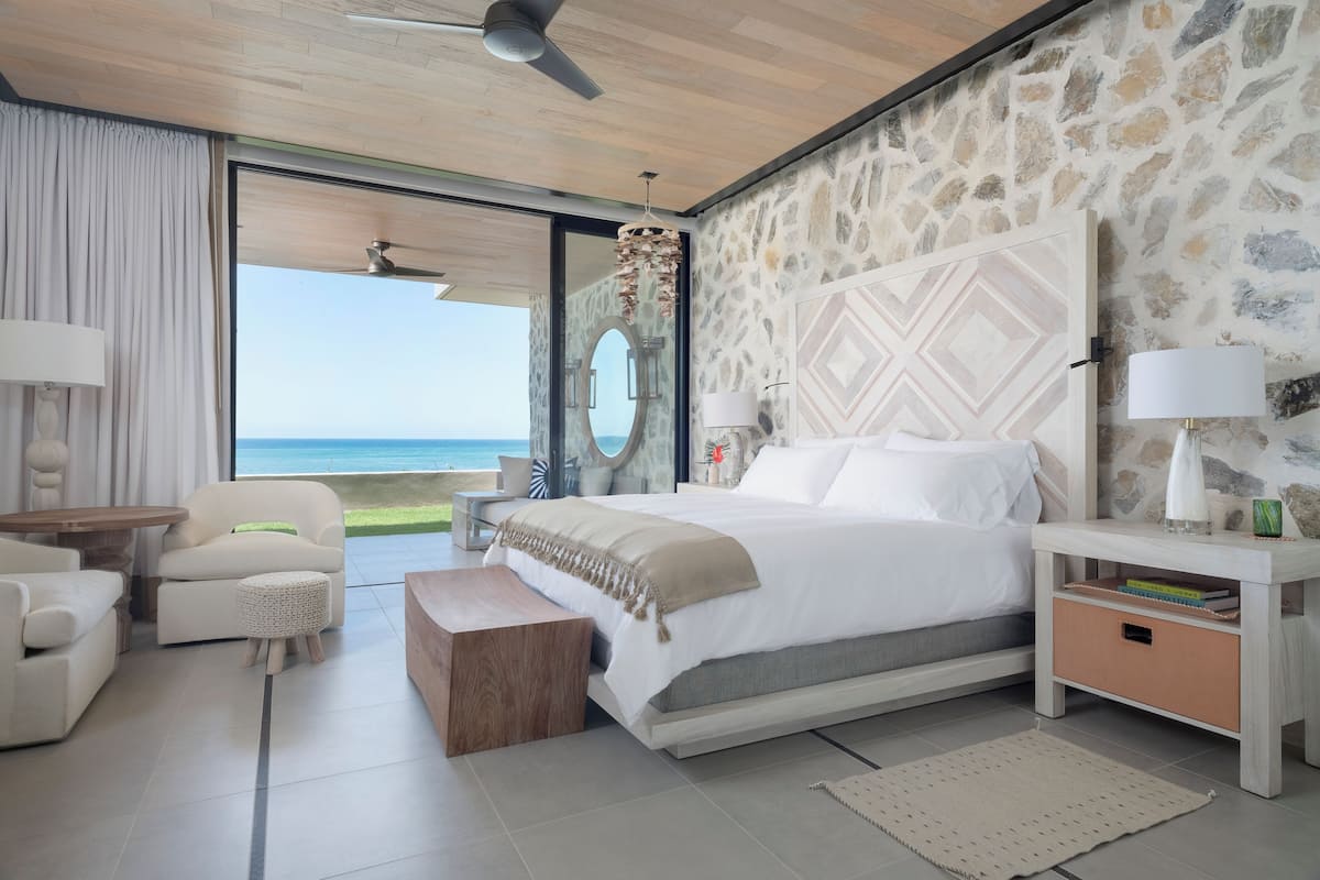 Un dormitorio moderno con una cama grande, una zona de estar y vista al océano.