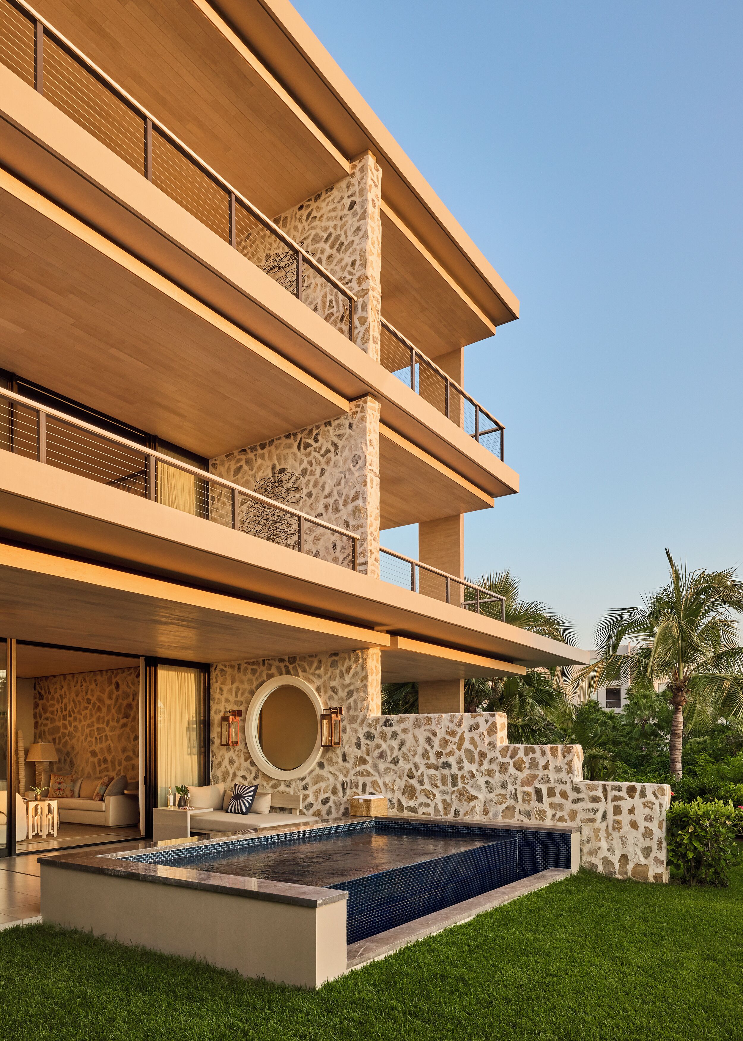 A multi-story building with a stone facade, a swimming pool, and a well-maintained lawn.