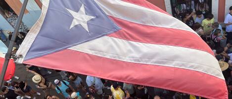 Una bandera grande con una estrella y franjas, sostenida por una multitud.
