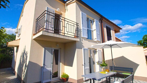 A two-story building with a balcony, a satellite dish, and a patio area with a table and chairs. - Holiday home mit Terrasse und Grill (Pula)