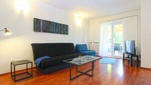 A living room with a black sofa, a coffee table, a TV, and a painting on the wall. - Holiday home mit Terrasse und Grill (Pula)