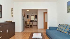 A living room with a sofa, a coffee table, and a kitchen in the background. - Holiday home with terrace and barbecue (Premantura)