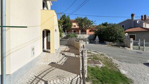 A residential street with a yellow building, a stone pathway, and a clear blue sky. - Holiday home with terrace and barbecue (Premantura)