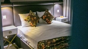 A hotel room with a bed, two nightstands, a bench, and two wall-mounted lamps.