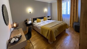 A hotel room with a bed, bedside tables, a desk, and a chair. There are wall sconces and a ceiling light. - EVASION Gîtes & Spa – A unique getaway in the heart of the Vosges (Saint-Léonard)