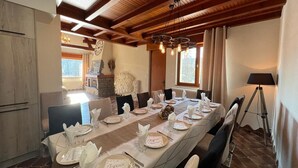 A dining room with a long table set for a meal, wooden beams on the ceiling, and a view of the outdoors. - EVASION Gîtes & Spa – A unique getaway in the heart of the Vosges (Saint-Léonard)