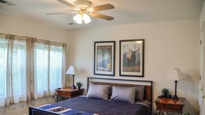 A bedroom with a bed, two nightstands, a ceiling fan, and two framed pictures on the wall. - Duplex Cabin at The Woolly Bugger Inn (#15) (Estes Park)