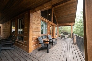 A wooden cabin with a covered porch, large windows, and outdoor seating.