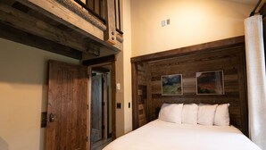 A bedroom with a wooden headboard, a bed with white bedding, a door, and a vent. - Mountain Lion Den at Snowcat Cabins (Hot Tub!) (Coram)