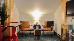 A cozy room with two leather armchairs, a small table, a lamp, and a television. - Marmot Mini Cabin (Unit 7) at The Woolly Bugger Inn (Estes Park)